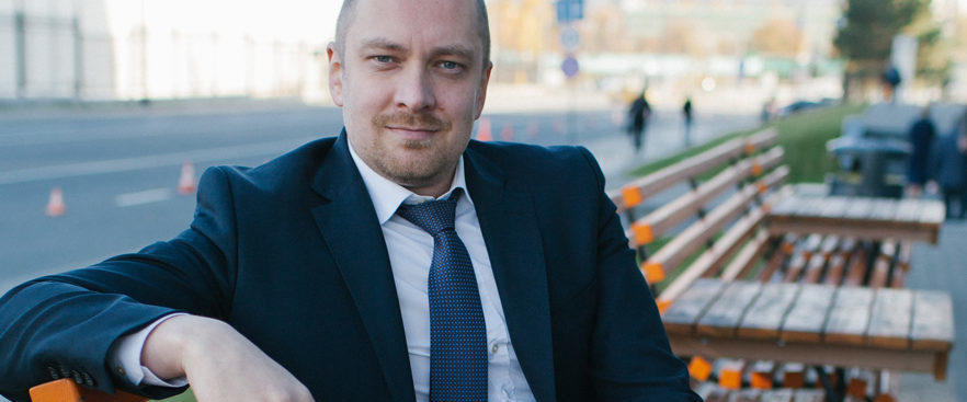 Kuvassa Venäjän kaupallinen edustaja Anton Loginov istuu puistossa penkillä ja katsoo kameraan.