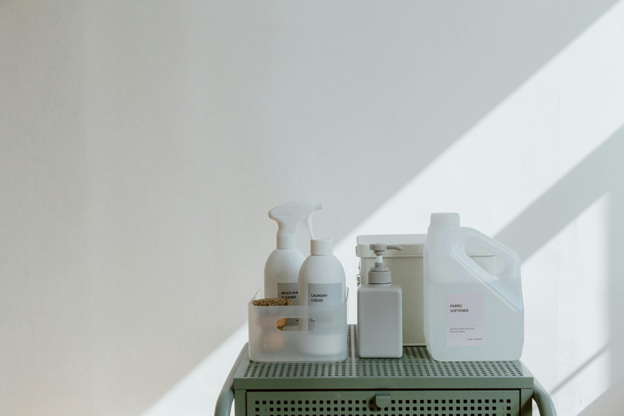 Cleaning and laundry products arranged on a shelf in a well-lit room.